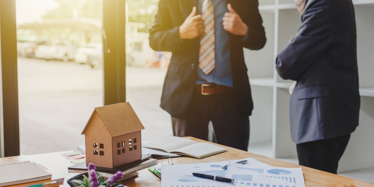 real estate deal being made in office paperwork on table with model house