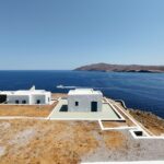 Stunning modern luxury villa featuring a bright infinity pool that overlooks a calm blue ocean, representing the high-end ...