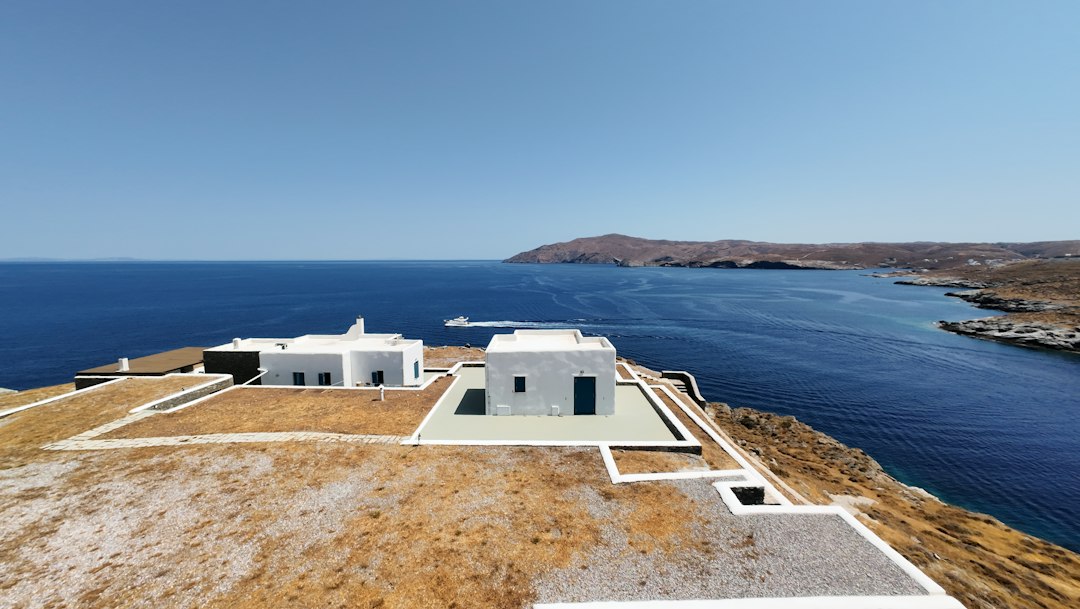 Stunning modern luxury villa featuring a bright infinity pool that overlooks a calm blue ocean, representing the high-end ...